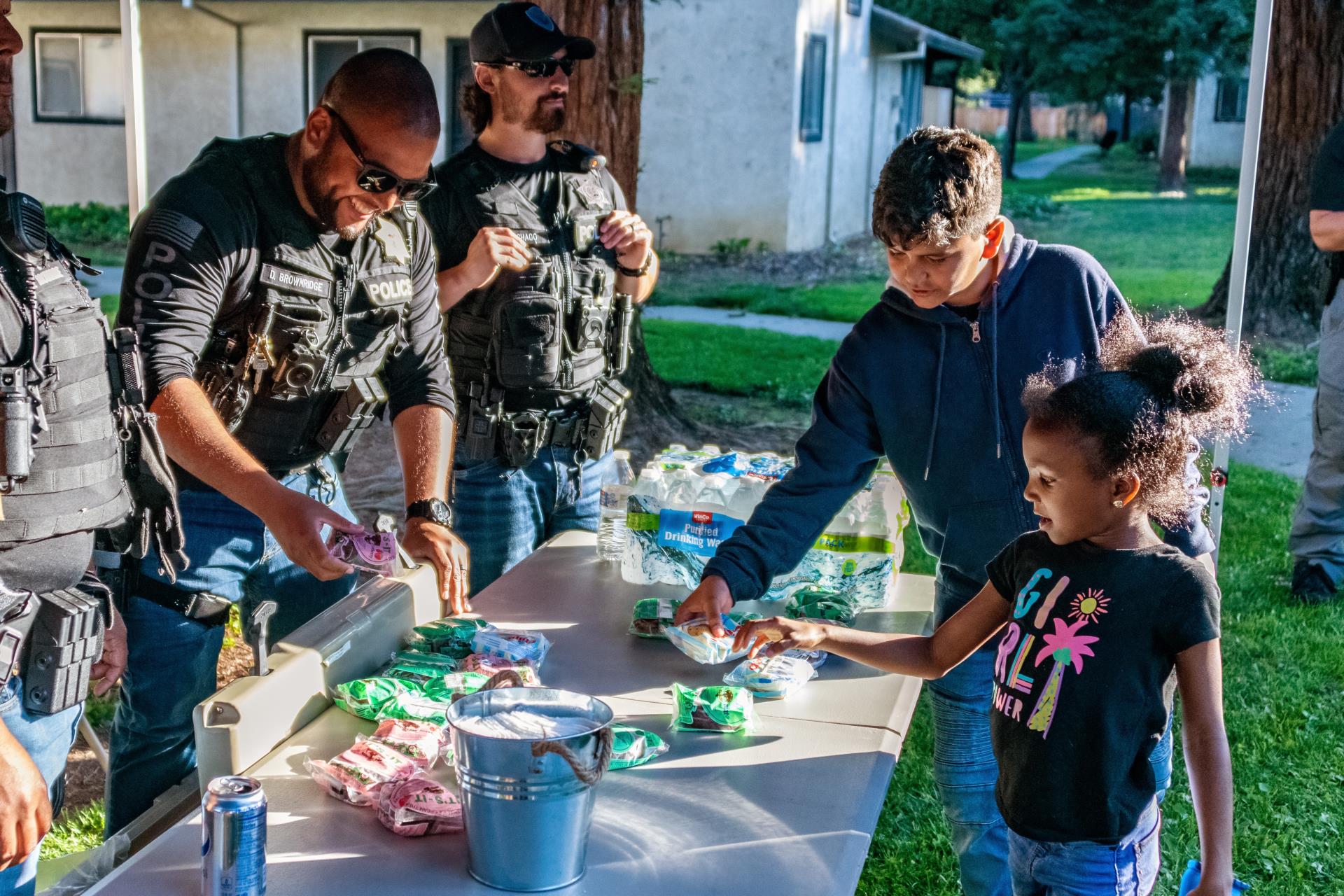 Officers at a table handing out gifts to kids